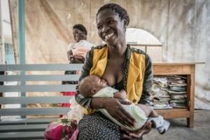 A mother smiles while breastfeeding a child