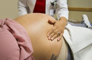 A doctor puts their hands on a pregnant belly