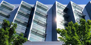 A modern building with sun glinting off the windows in front of a blue sky